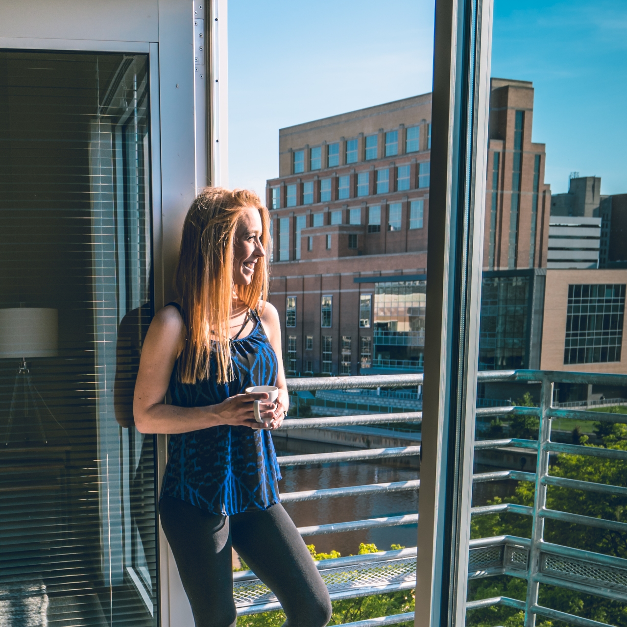Woman looking out over a balcony overseeing the Grand River in downtown Lansing